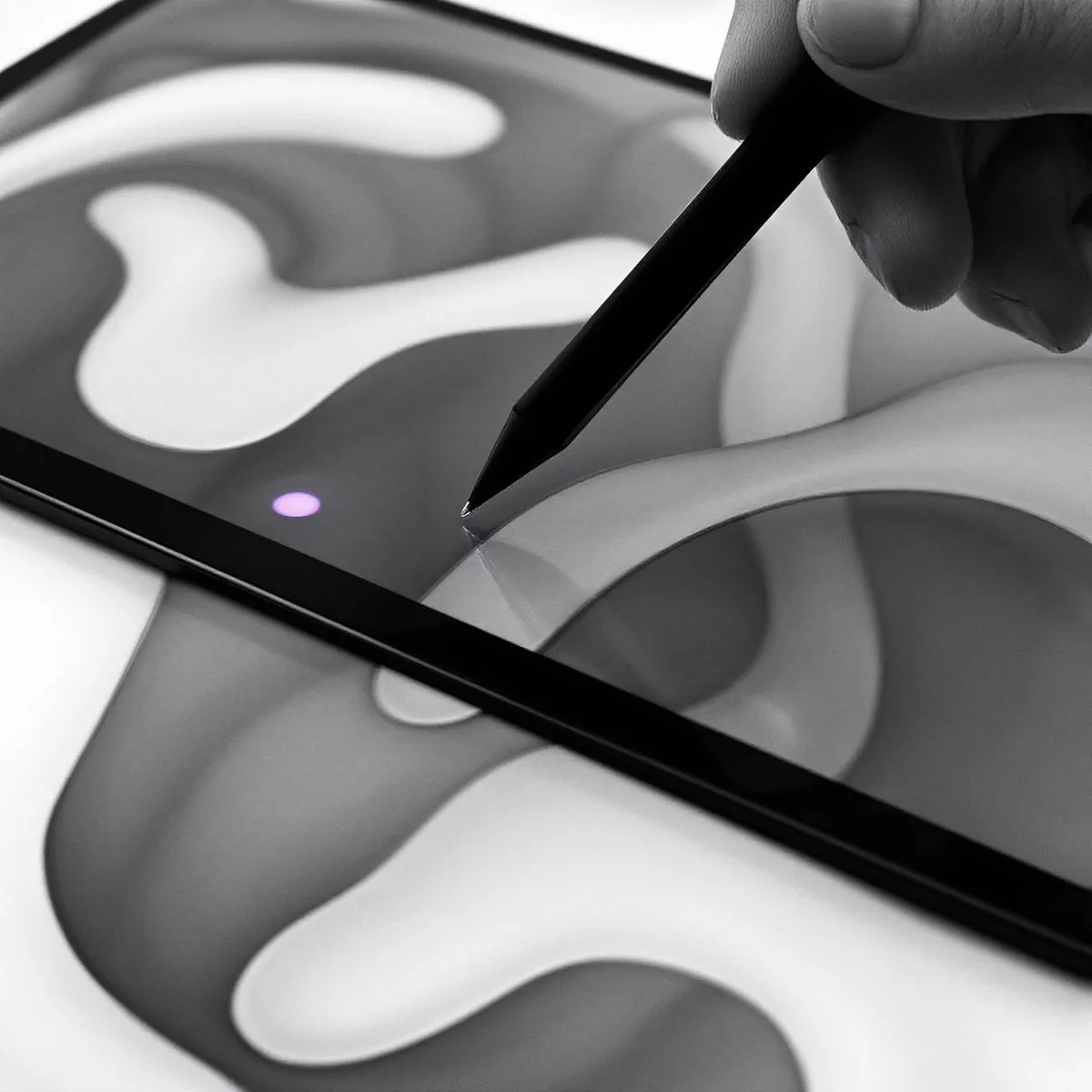 Mão com uma caneta digital sobre a tela de um tablet com formas abstratas em preto e branco e um ponto roxo